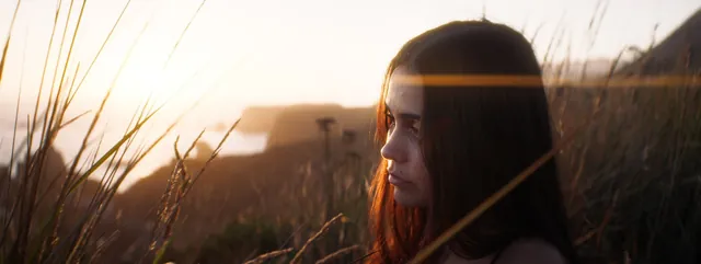 Cinematic profile among tall coastal grass at sunset.
